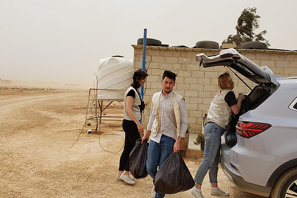 Freiwillige von URI MENA tragen gespendete Essenspakete aus dem Auto. Damit unterstützen sie den Ramadan Kareem Community Service in einer syrischen Flüchtlingsgemeinde.