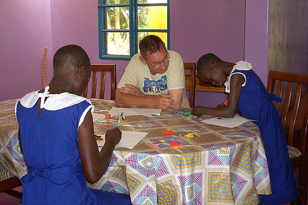 AGIAMONDO-Fachkraft Alfred Pfeifer arbeitet mit zwei Schülerinnen im Internat für Kinder mit Lernbehinderung.
