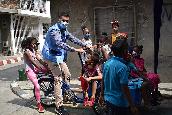 Cristián Rebellón (links) von der Land- und Präventionsdiakonie wird von Kindern eines Stadtviertels  umringt. Er besuchte das Viertel in Cali anlässlich des Wettbewerbes "Ökologische Krippen".