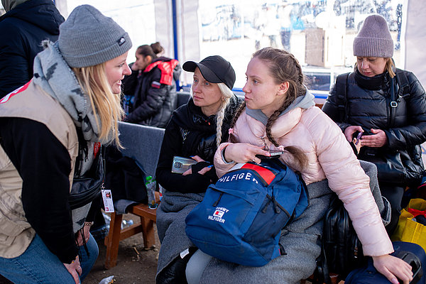 Henrike Bittermann (links) spricht mit zwei Frauen, die gerade aus der Ukraine angekommen sind.  Die Caritas-Mitarbeiter*innen suchen das direkte Gespräch, um zu verstehen, was die Menschen brauchen.