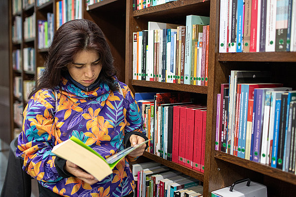 Die kolumbianische Friedenspädagogin, Catalina Quiroga Pardo, schaut sich in der Bibliothek des Zentrums für Erinnerung, Frieden und Versöhnung Literatur zur Thematik an.