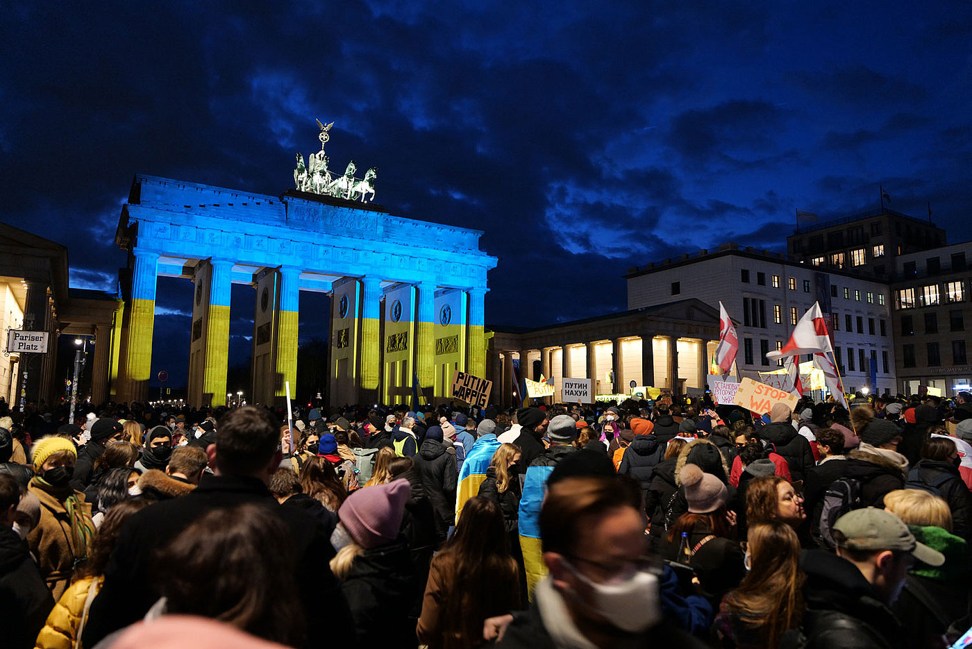 Kundgebung auf dem Pariser Platz in Berlin gegen den militärischen Angriff Russlands auf die Ukraine vor dem mit der ukrainischen Flagge beleuchteten Brandenburger Tor am 24.2.2022