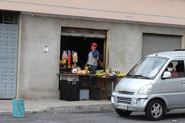 Ein Mann verkauft Obst und Gemüse aus einem Stand in Quito. 